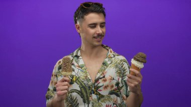 Genç İspanyol adam canlı mor arka planda dondurmayı seviyor. Tropikal gömlek ve güneş gözlüğü takıyor. Neşeli bir turist havası var..