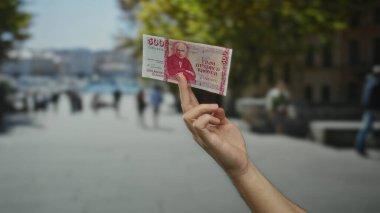 Arka planda insanların olduğu bir şehir caddesinde İzlanda Krona banknotu tutan bir adam, ekonomik değişim ve para birimini Avrupa 'da bir şehir merkezinde açık havada kullanıyor..