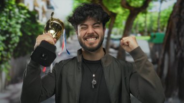 Genç adam zaferi açık havada zaferle kutluyor coşkulu bir sokakta ezici bir neşe ve başarı gösteriyor..