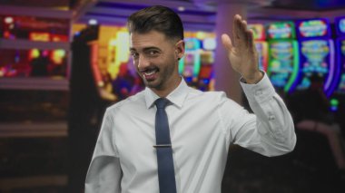 Kumarhane binası lobisindeki parlak slot makinelerinin yanında adam selamlıyor; sıcak karşılama.