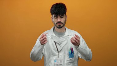 Beyaz laboratuvar önlüklü genç adam canlı turuncu bir arka plana karşı maske takarak profesyonel ve ihtiyatlı bir atmosfer yaratıyor..