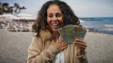 Sahilde gülen ve elinde Romanya banknotları tutan bir kadın, deniz kenarında tatil ve refah öneriyor..