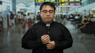 Dolu bir havaalanı terminalinde gezginlerle çevrili, parlak havaalanı tabelası altında endişeli bir ifade sergileyen Çinli bir rahip seyahat endişesi ve kültürel varlığı iletiyor..