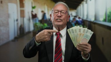 Bir restoran terasında Czech Koruna banknotları tutan kıdemli bir adam açık hava sokak ortamında iş ve finansal başarıyı resmediyor..