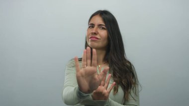 İzole edilmiş beyaz arkaplan karşısında el kol hareketi yapan, reddeden ya da inkar eden genç İspanyol kadın reddedilme duygusunu ifade ediyor..