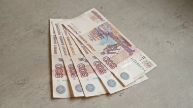 Beton bir yüzeye yerleştirilmiş Rus banknotları, servetin ve para biriminin sergilendiği hayran olunan bir ekranda birden fazla 500 ruble banknotun altını çiziyor..