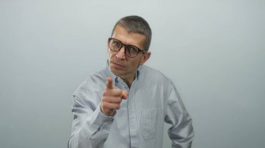 Gözlüklü, çizgili tişörtlü bir adam kameraya beyaz bir arka planda özgüvenli bir şekilde bakarken, bir anlık bir nişanlanma görüntüsü yakalıyor..