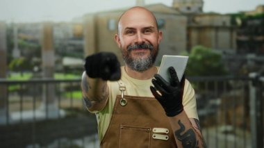 Antik Roma harabelerine karşı elinde defterle açık havada poz veren siyah eldiven ve önlük giyen bir adam, modern modayla tarihi mimarinin bir karışımını örnek gösteriyordu..