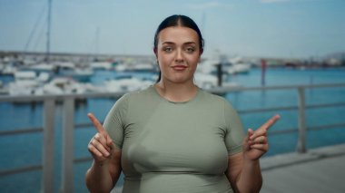 Kadınlar, deniz kenarındaki marinada teknelerle ve açık gökyüzüyle barışçıl bir açık hava manzarası yaratarak el kol hareketi yapmazlar..