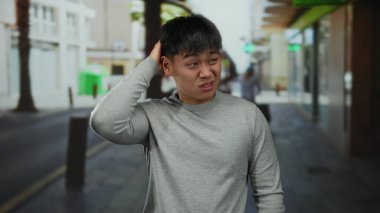 Gündüz vakti şehrin arka planında dikilirken rahatsız edici ya da kafa karıştırıcı davranışlar sergileyen genç bir adam..