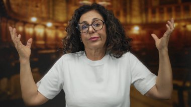 Orta yaşlı İspanyol kadın kilisenin içinde konuşma jesti için el kullanır; iletişim ifadesi nişanı.