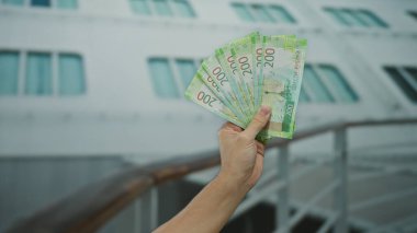 Deniz kıyısındaki bir yolcu gemisinde banknotlarla el ele tutuşan Rus rubleleri, açık deniz ortamında seyahat lüksünü ve finansal başarıyı resmediyordu..