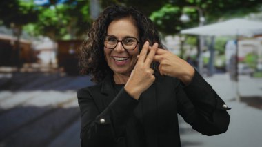 İşlek bir sokakta parmaklarıyla hashtag jesti yapan İspanyol kadın; sosyal medya eğilimi bağlantısı.