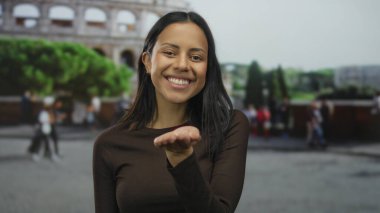 Roma Kolezyumu 'nun dışındaki kameraya gülümseyen ve öpüşen bir kadın canlı bir sokak ortamında genç bir İspanyol kadınla neşeli bir anı yakalıyor..