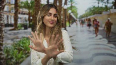 Kadın avuçlarını ileri doğru tutar, avuçlarında neşeli bir gülümseme, kendine güven dayanıklılığı..