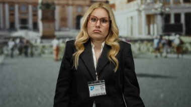 Siyah takım elbiseli genç sarışın kadın antik Roma harabelerinin önünde modern ve tarihi manzaraları dinamik bir şekilde harmanlıyor..