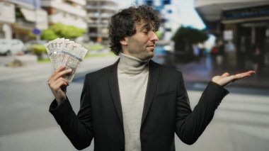 Bir şehir caddesinde İspanyol bir adam elinde Suudi riyal banknotlarıyla zenginlik ve refah kavramını ortaya koyuyor.