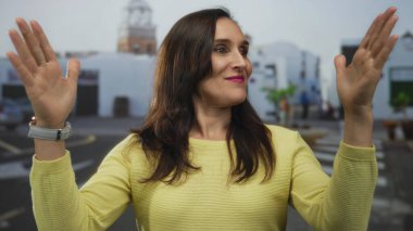 Genç İspanyol kadın tarihi bir meydanda duruyor ve elleriyle büyük bir jest yapıyor; ölçü karşılaştırması..