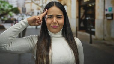 Bir kadın, genç Latin asıllı, açık hava figürünün kendine güveni tam bir şekilde durduğu bir sokakta elini kaldırır..