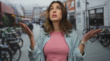 Çevresi bisiklet ve şehir manzarasıyla çevrili, hareketli bir şehir sokağında hareketli genç İspanyol kadın, açık havada günlük giysiler ve kol saati giyiyor..