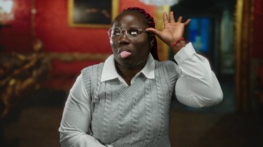 Kırmızı müzenin arka planında neşeli bir şekilde gülümseyen bir kadın çerçeveli sanatla sıradan bir atmosferin eğlenceli etkileşim önerdiği bir yerde.