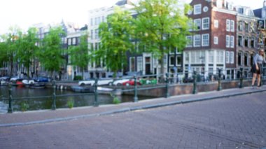 Bulanık bir kadın Bokeh efektli amfi kanallarında yürüyor. İkonik Hollanda mimarisi ve sakin deniz manzaraları yakalıyor..