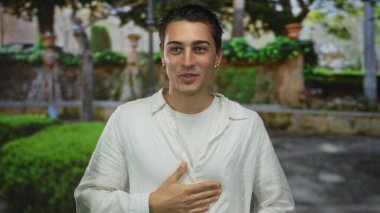 Beyaz tişörtlü genç İspanyol, yemyeşil ve taştan yollarla çevrili yemyeşil bir parkta huzurlu bir anın tadını çıkarıyor.