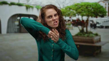 Gündüz vakti arka planda modern mimari ile şehir sokaklarında ifade edilen hareketler yapan kadın.