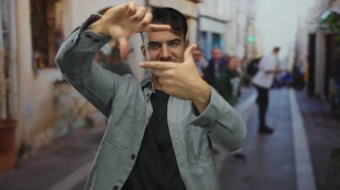 Genç İspanyol asıllı bir adam, şehir sokaklarında hareketli bir el hareketleriyle fotoğraf sanatında yaratıcılığını ve hareketliliğini gösteriyor..