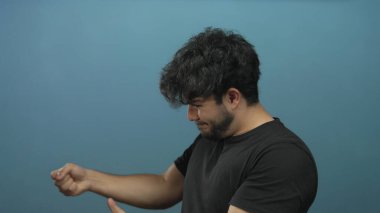 Sakallı genç bir adam mavi bir arka plana ip çekiyor gibi yapıyor, oyuncu ve yaratıcı bir aksiyon konseptini tasvir ediyor..