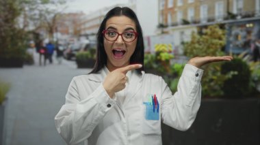 İspanyol üniformalı kadın bilim adamı hareketli bir şehir caddesinde iyi bir tabela yapıyor, şehir ortamında güven ve pozitiflik gösteriyor..