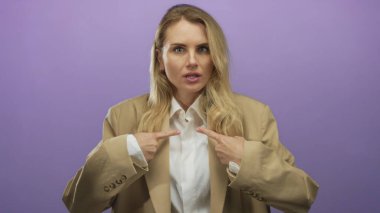 Bej takım elbiseli kadın, mor izole edilmiş arka plan karşısında şaşırmış bir ifadeyle modern ortamda şaşkınlık ve merak içinde..