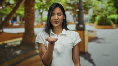 Parktaki genç İspanyol kadın kameraya öpücük yolluyor. Çevresi yeşillik ve şehir manzarasıyla çevrili. Dışarıdaki sıcaklığı ve arkadaşlığı ifade ediyor..