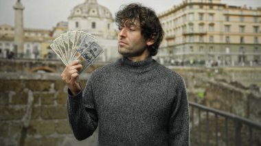 Bir şehir caddesinde Amerikan dolarlarını elinde tutan adam finans başarısını ve şehir yaşam tarzını resmediyor, açık havada zenginliğin cazibesini vurguluyor..