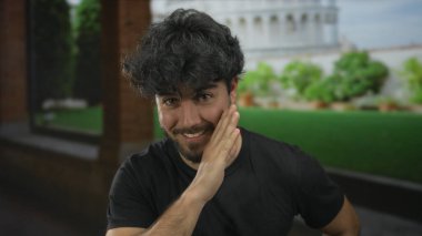 Sakallı genç adam güneşli bir günde sidik kulesinin yanında gizli bir jest yapar. İtalya 'da seyahat deneyiminin canlı ruhunu yakalar..