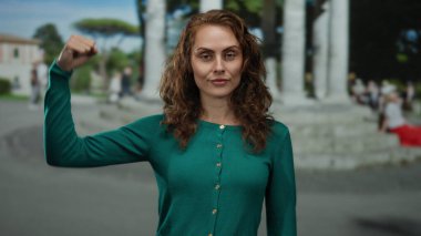 Kadın açık bir günde şehir ortamında kolunu rahatça uzatıyor. Güç ve güç katıyor ve şehir manzarasıyla donatıyor..