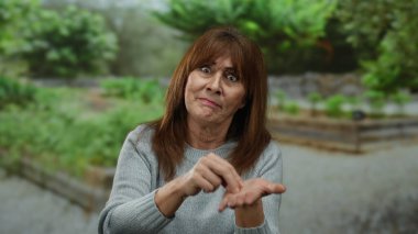 Parktaki son sınıf öğrencisi İspanyol kadın, açık hava ortamında duygu gösterisi yapan yemyeşil bir ortam ile çevrili..