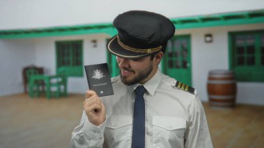 Dışarıda üniformalı bir adam güneşli bir günde Avustralya pasaportu taşıyor ve kırsal zemine gülümsüyor..