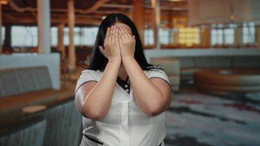 Kapalı alanda gülümseyen kıvrımlı bir kadın, modern bir otel ortamında eğleniyor, neşeli hareketleriyle neşeli duygularını ifade ediyor, sofistike atmosferi aydınlatıyor..