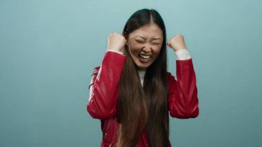 Kırmızı ceketli, mavi arka planda gülümseyen bir kadın güven ve neşeyle barış işareti gösteriyor..