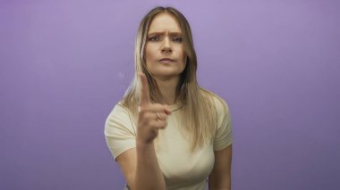 Mor arka plana karşı ciddi bir ifadeyle işaret eden bir kadın. Otorite ve odaklanma, izole edilmiş, el hareketi, genç ve kendinden emin.