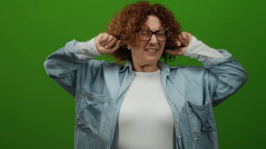 Yeşil arka planda kulakları olan bir kadın orta yaşlı, kıvırcık saçlı ve gözlüklü bir İspanyol görünümünü sergiliyor..