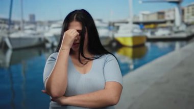 Bir kadın açık deniz limanında teknelerle dikiliyor. Huzurlu sahil manzarası ve güneşli hava ortamında endişeli ve duyguları somutlaştırıyor..