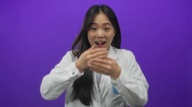 Mor arka planda beyaz üniformalı genç Çinli kadın bilim adamı elleri ağızlarını kapayarak şaşkınlıklarını dile getiriyor..