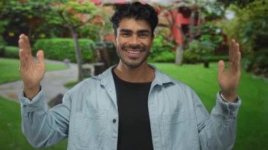 İspanyol adam gülümserken bir binanın önünde kollarını açıyor; sevinç iyimserliği kutlaması.