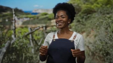 Parkta önlük takmış gülümseyen bir kadın, güneşli bir günde mutluluk ve açık hava aktivitesi sergiliyor..