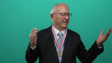 Madalya mimikleri olan yaşlı bir adam canlı yeşil bir altyapının önünde ödül sahibi bir iş adamını canlandırıyor..