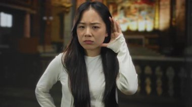 Güzel dekore edilmiş bir kilise ortamında meraklı bir ifadeyle dinleyen bir kadın, dalgın ve düşünceli bir atmosferi ön plana çıkarıyor..