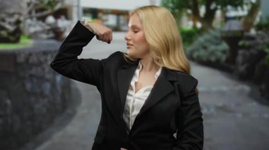 Şehir merkezinde resmi takım elbise giyen bir kadın, yeşil yeşillik ve sokak geçmişi arasındaki güven ve gücü sembolize ediyor..