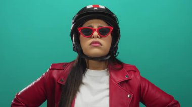 Kadın, arka planda yeşil izole edilmiş arka plan çerçeveli genç Latin kasklı sürücünün yumruk duruşu sırasında avucunu kaldırıyor..